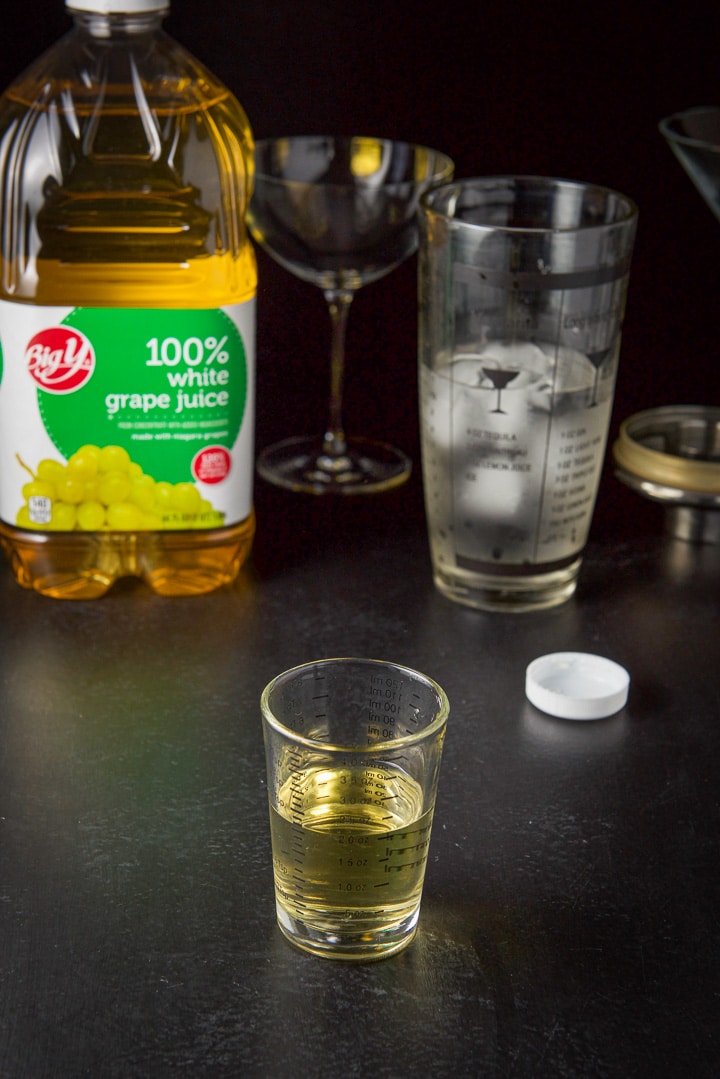 White grape juice poured with the bottle, shaker and glasses