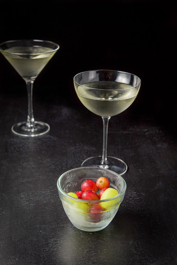 Grapes fresh out of the freezer in front of the two glasses filled with the cocktail