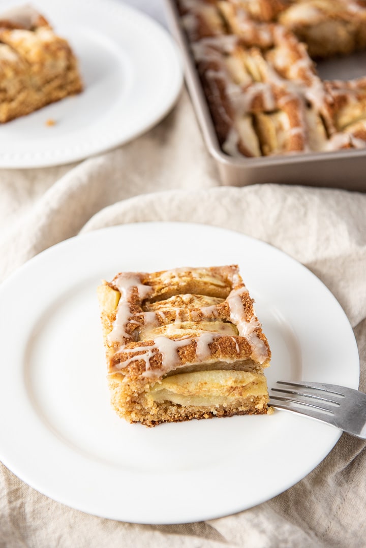 Close up of the cake on a white plate with another piece behind it and the cake pan