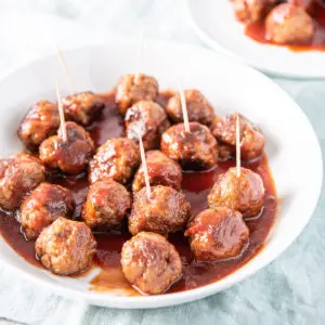A white plate with bourbon meatballs on it