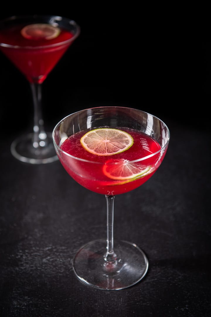Almost overhead view of the cosmo in the bowl glass with two lime wheels floating in them