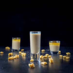 Tall glass of the layered shot along with two others on the table - square