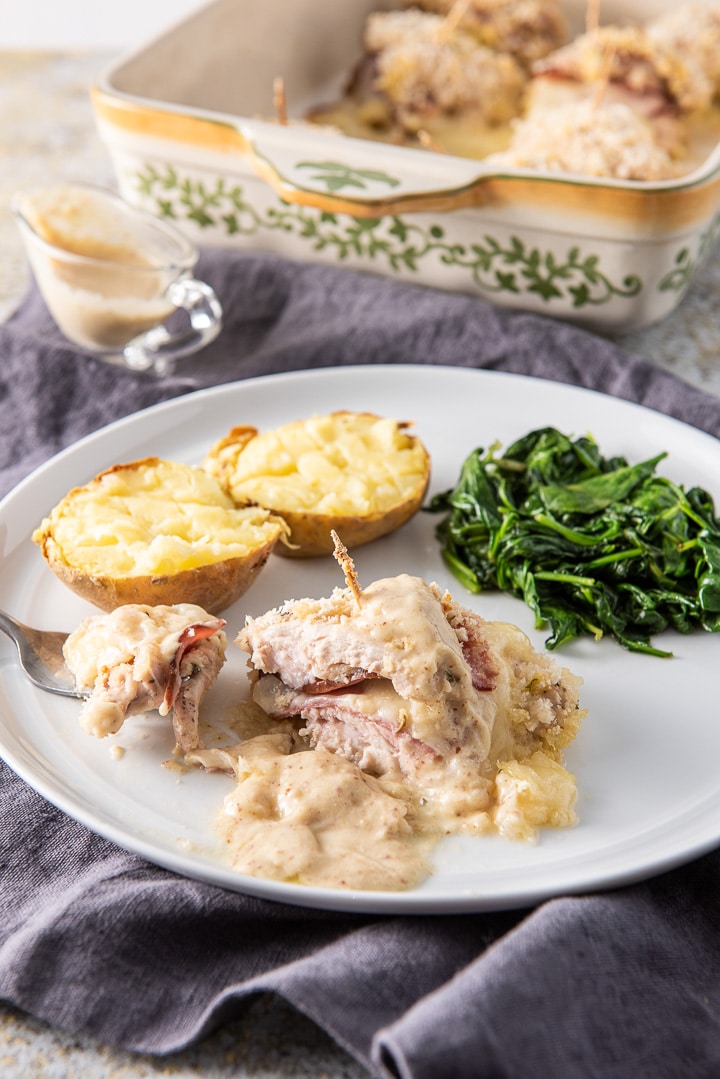 Bite of the chicken on a fork with a potato and spinach on the side