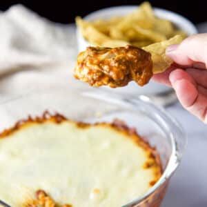 A chip scooped with cheese dip - square