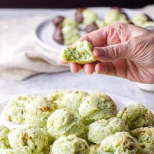 Hand holding one of the cream cheese pistachio cookies with a bite taken out of it