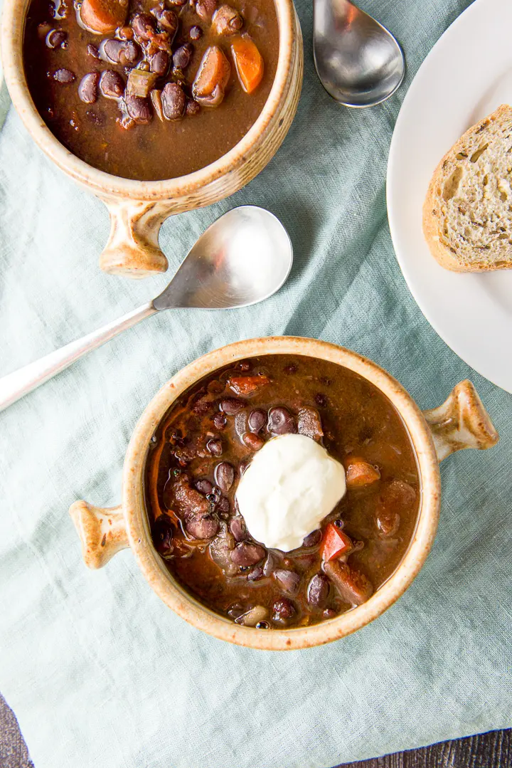 Overhead view of the black bean soup with sour cream and a plate with bread