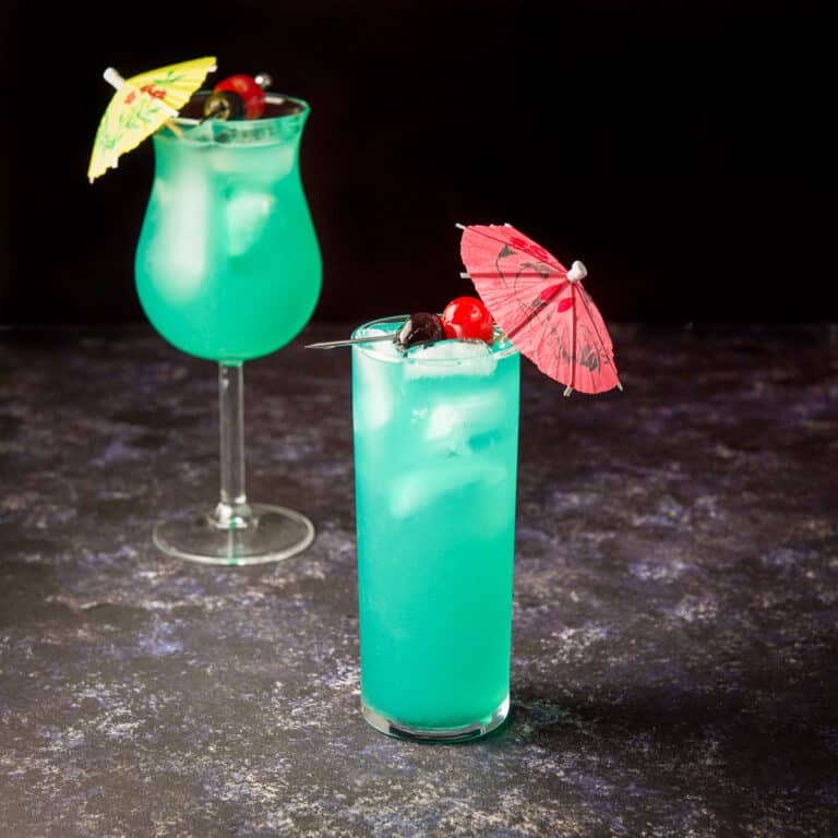 Collins glass in front filled with the blue fruity cocktail - square