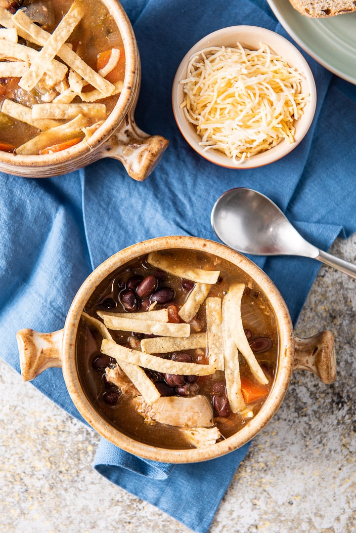 Overhead view of the tortilla soup with cheese and a corner of bread