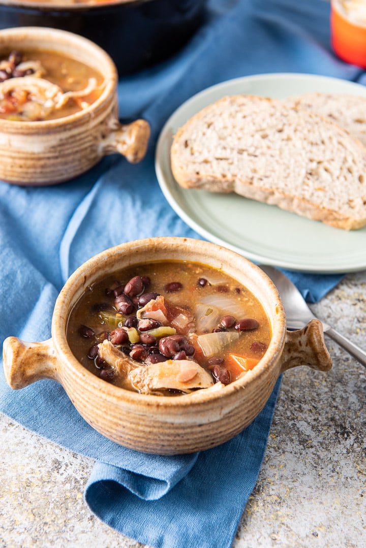 Chicken tortilla soup in a crock with bread in the background