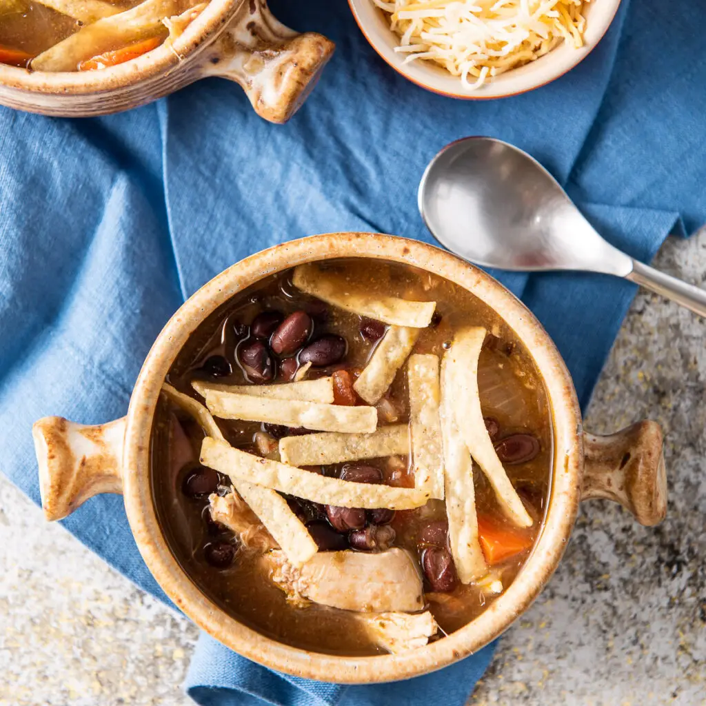 Overhead view of crocks of tortilla soup with tortilla strips on top - square