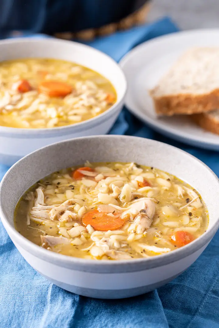 Closer view of the chicken soup in two bowls with bread in the background