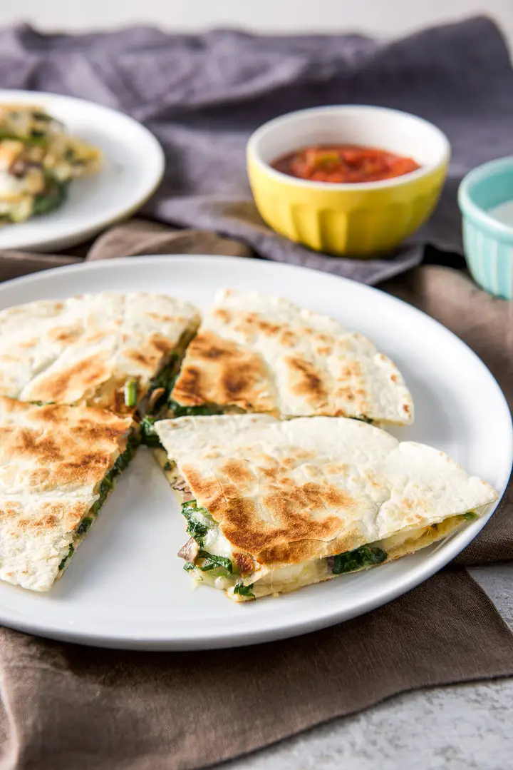 Closer view of the quartered mushroom and spinach quesadilla on the plate