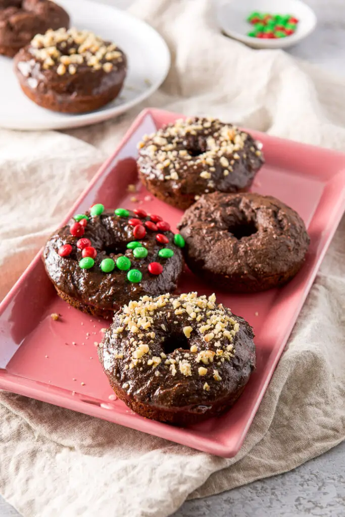 Nut covered chocolate donuts on a pink plate