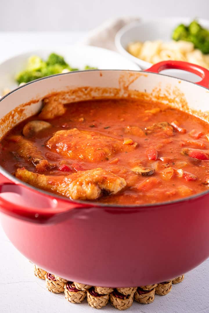 Pan of the fully cooked chicken with plates in the background