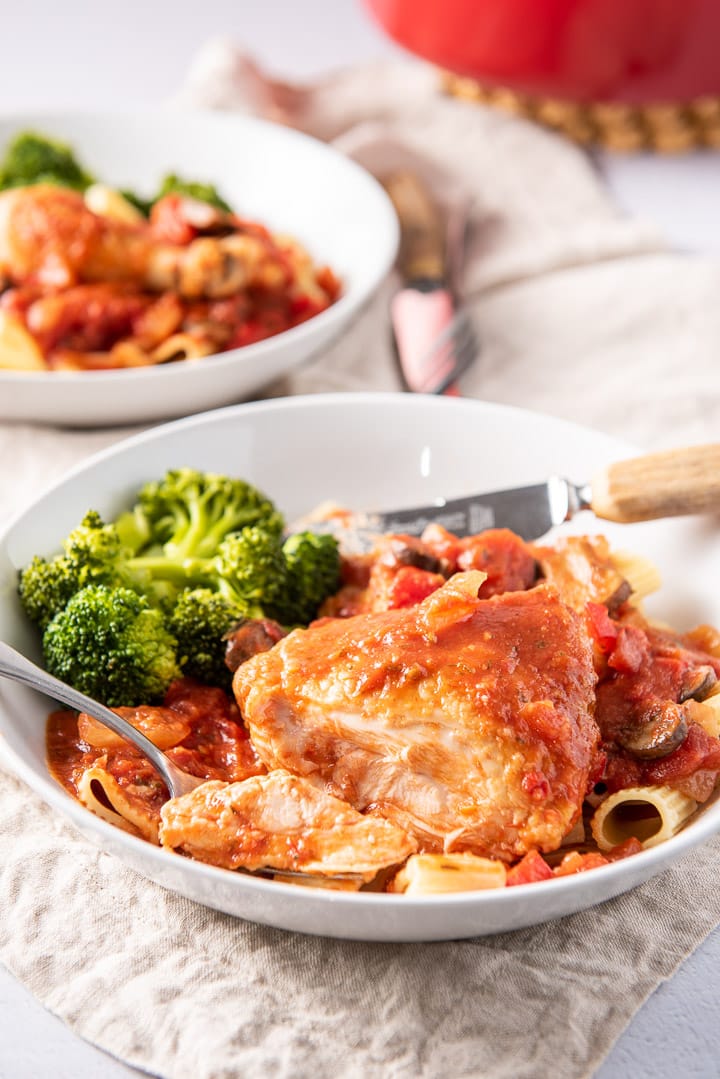A forkful of chicken in a plate with the thigh and broccoli next to it