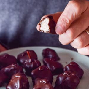 A male hand holding a mounds bar with a bite taken out of it - square