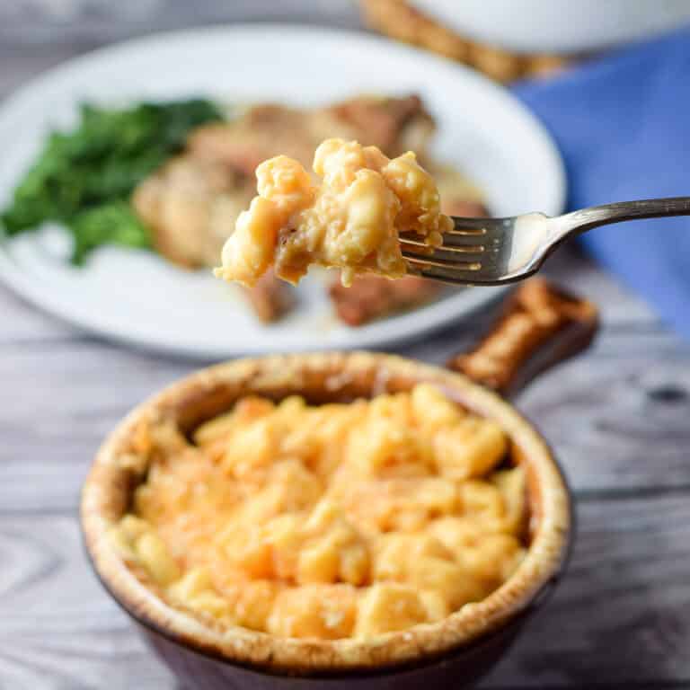 A forkful of cheesy macaroni over a crock filled with it