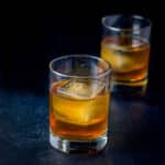 Two old fashioned glasses filled with the godfather cocktail - square