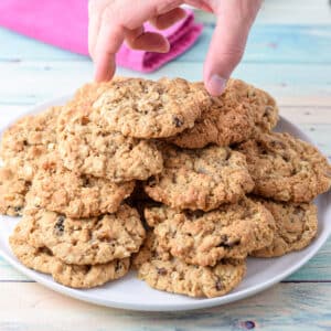 A man grabbing a cookie of a pile of them on a white plate