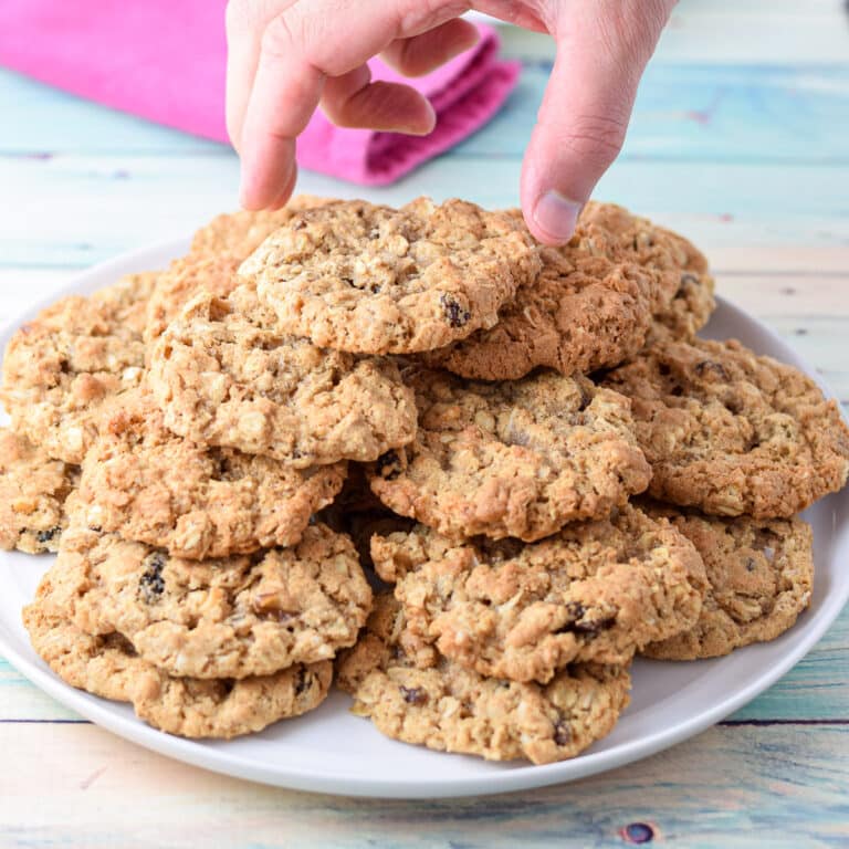 A man grabbing a cookie of a pile of them on a white plate