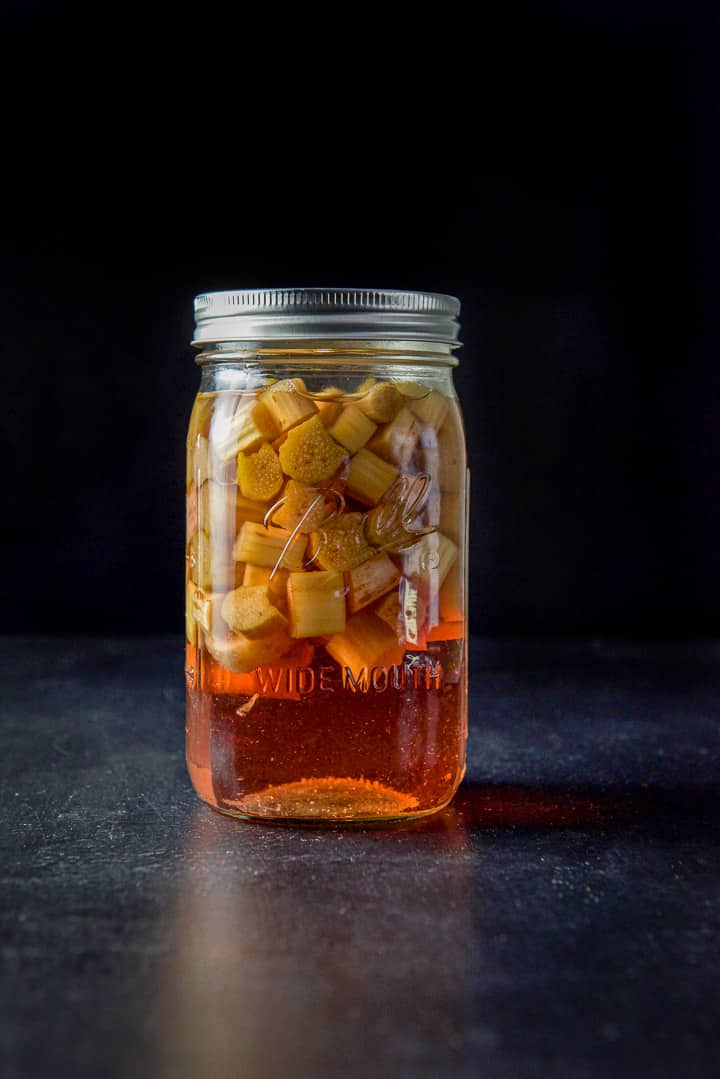 A jar of leeched rhubarb floating at the top and the red infused vodka on the bottom