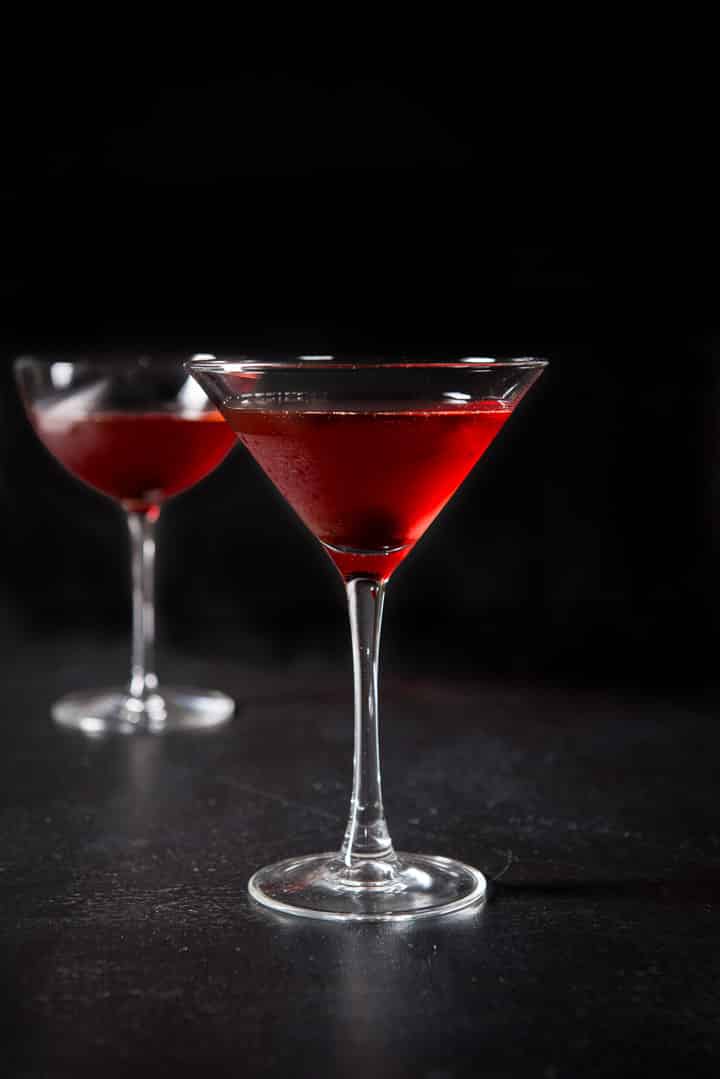 Vertical view of the classic martini glass filled with the Manhattan with the bowl glass behind it