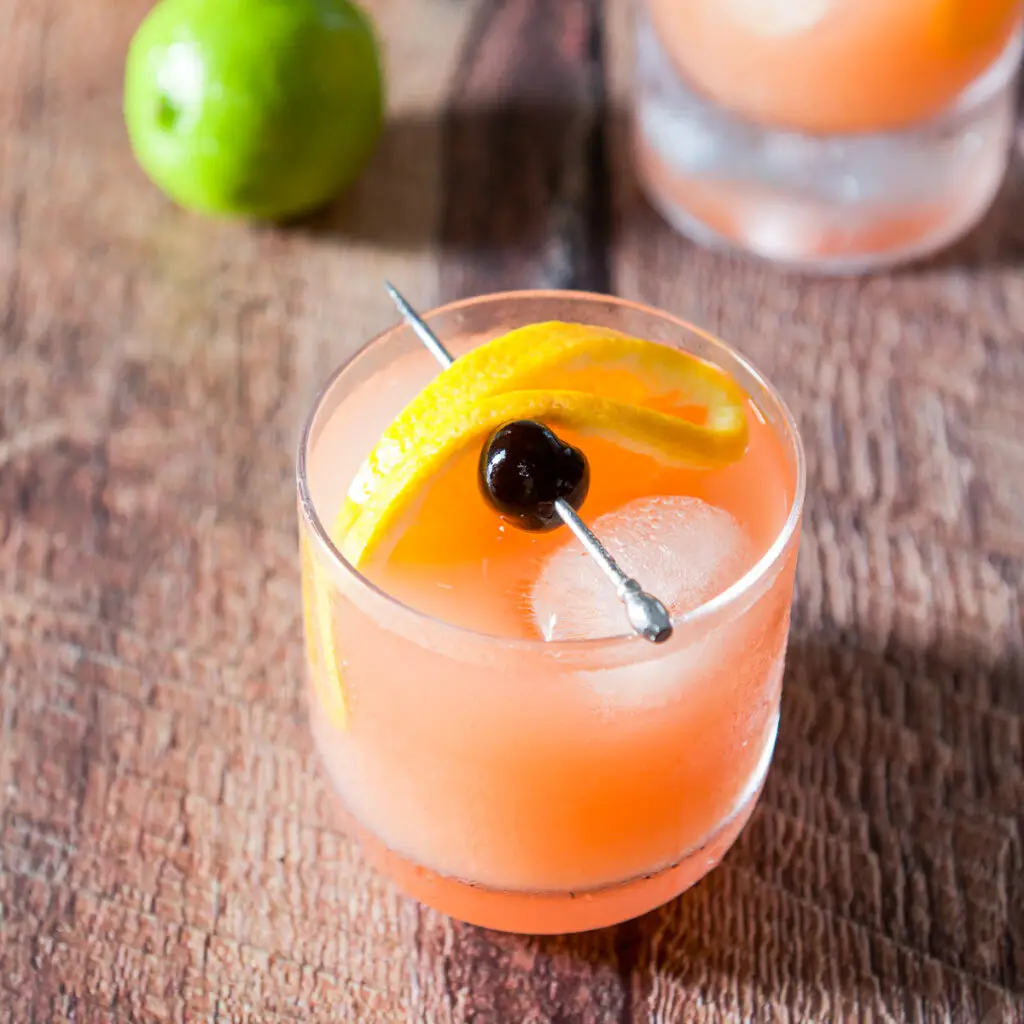 A double old fashioned glass filled with the mai tai with a cherry and orange slice on a pick