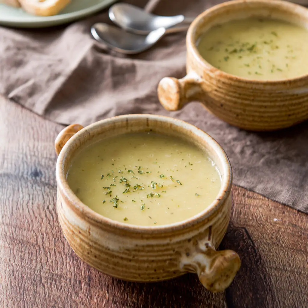 Two crocks filled with potato soup with parsley on top - square