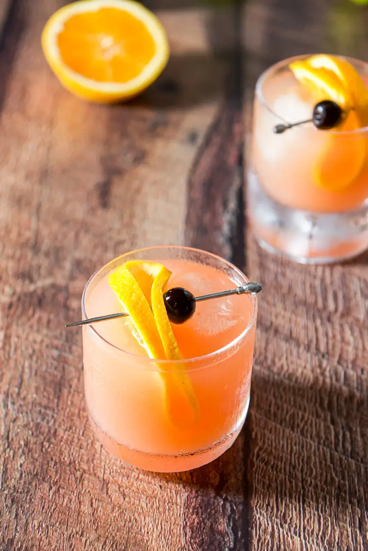 Two mai tais with slices of orange and cherries for garnish