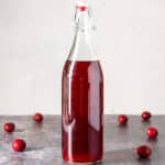 A tall bottle of cherry vodka with cherries on the table - square