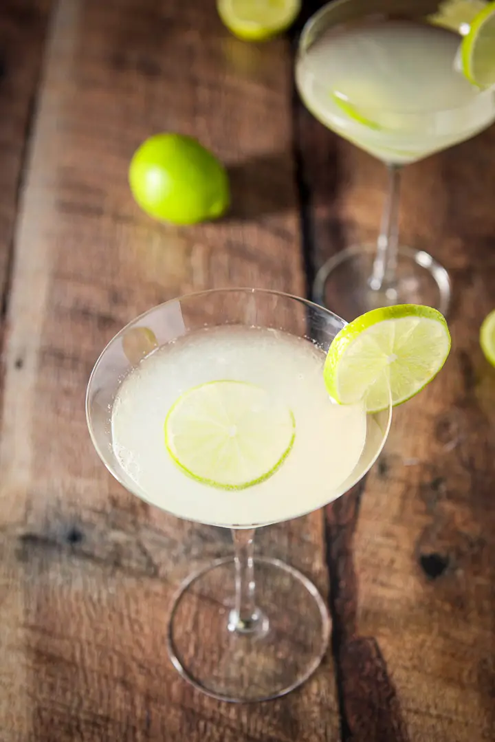 Almost overhead view of the classic martini glass filled with a lime cocktail with lime wheels floating in the liquid and on the rims
