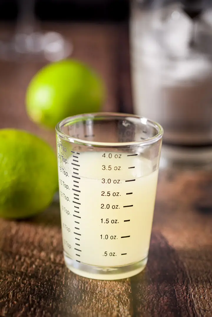 Lime squeezed out and measured with more limes and the shaker in the background