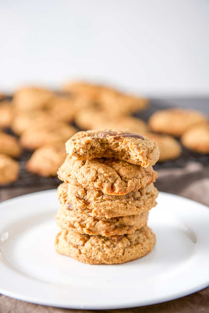 A stack of five cookies, the top one with a bite taken out of it