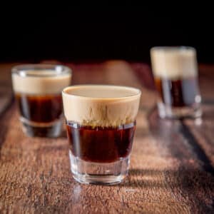 Three glasses with the layered shot in it with the beveled glass in the front