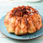 Pull apart bread with a glaze on it on a blue plate - square