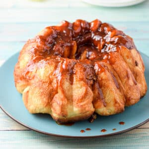 Pull apart bread with a glaze on it on a blue plate - square