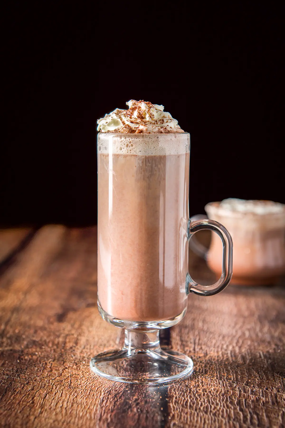 Vertical view of the tall mugh with the chocolate drink, whipped cream and cocoa on top