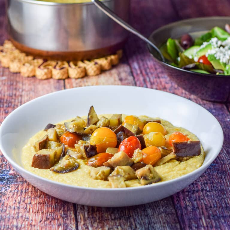 a white plate with polenta and tomatoes and eggplant - square