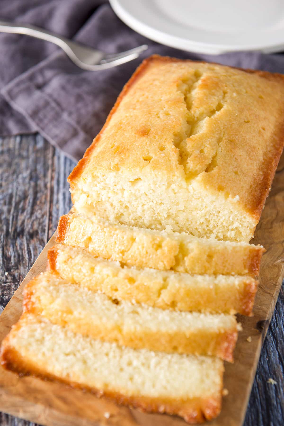 A wooden board with the lemon bread cut in four slices