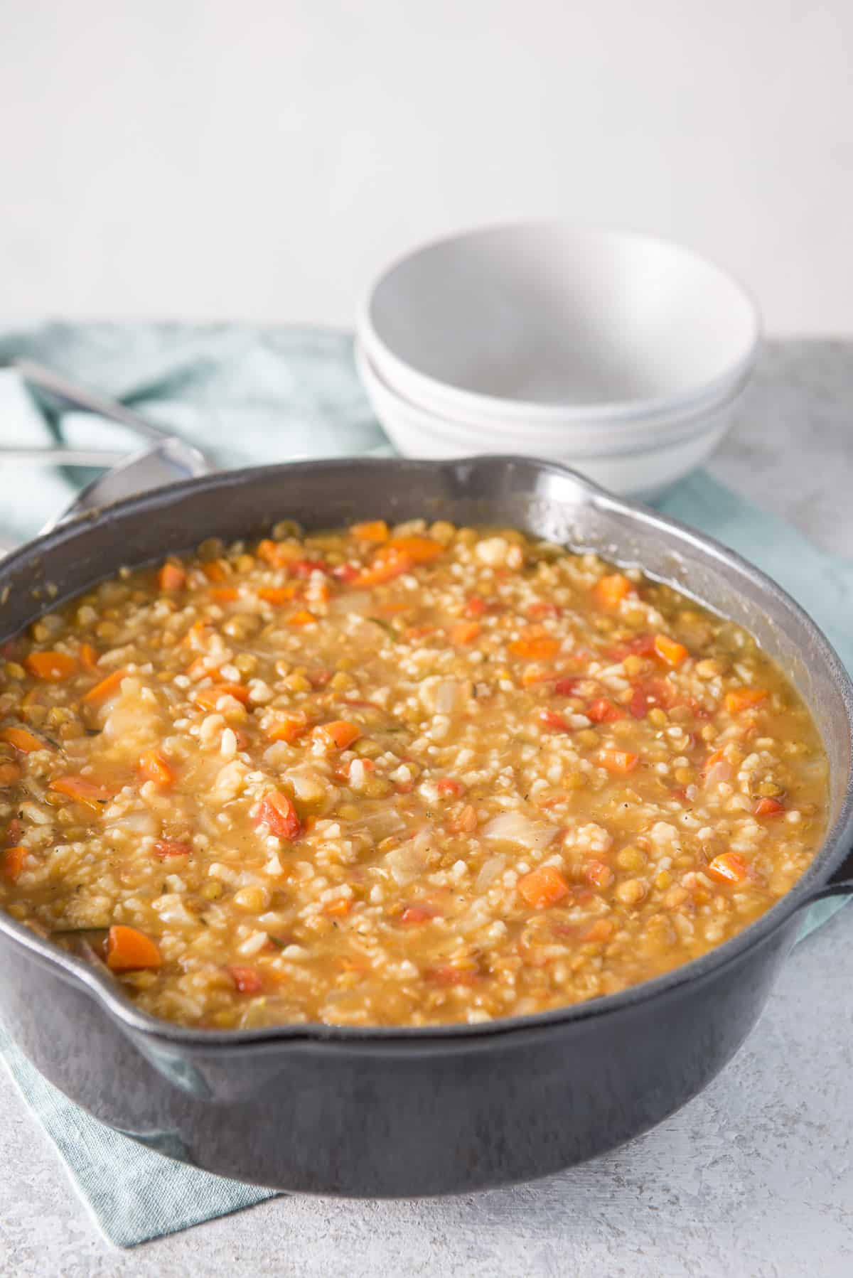 A big dark grey cast iron pan filled with the instant pot soup with two grey bowls in the background