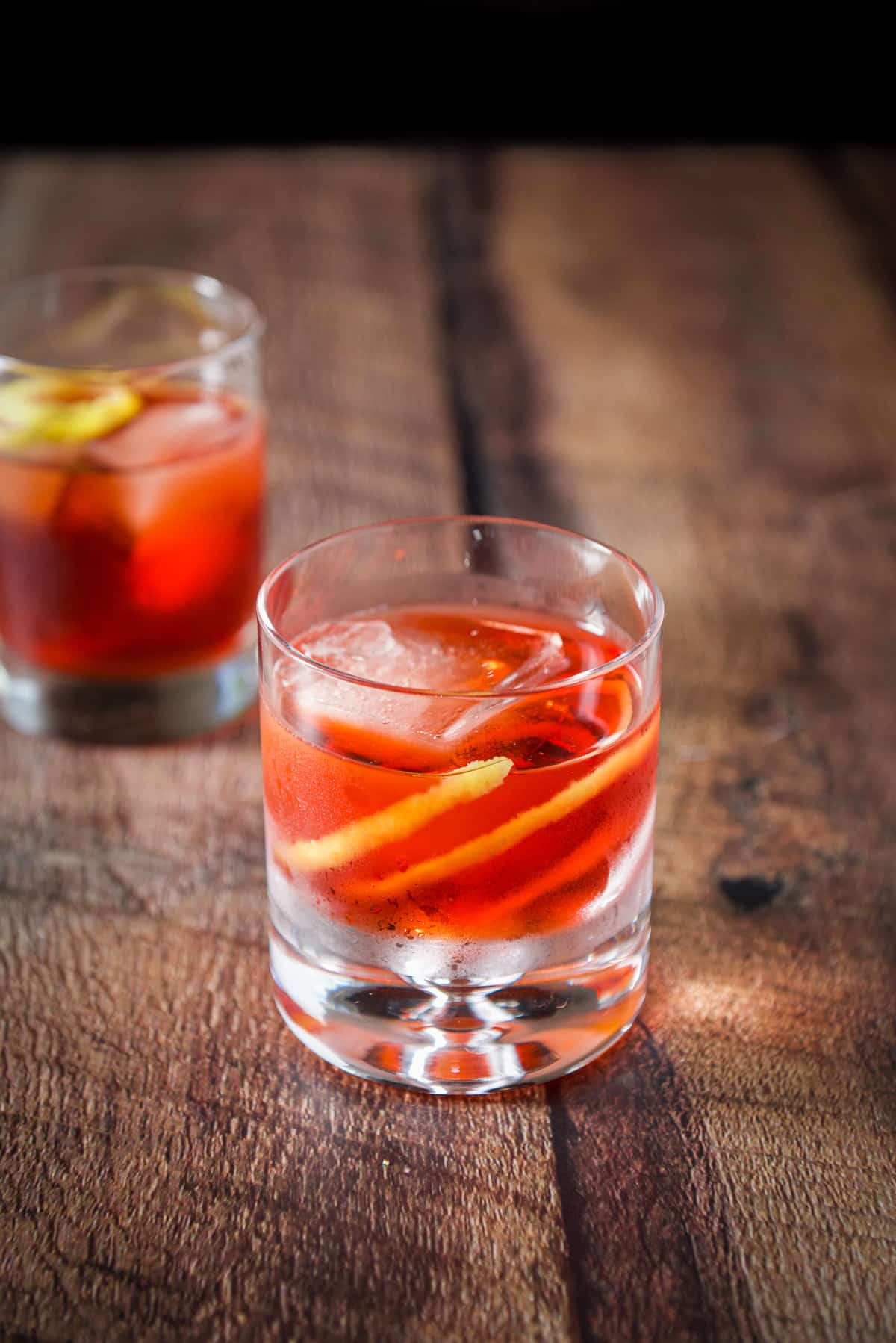The bubble glass in front of the taller double old fashioned glass filled with the red cocktail