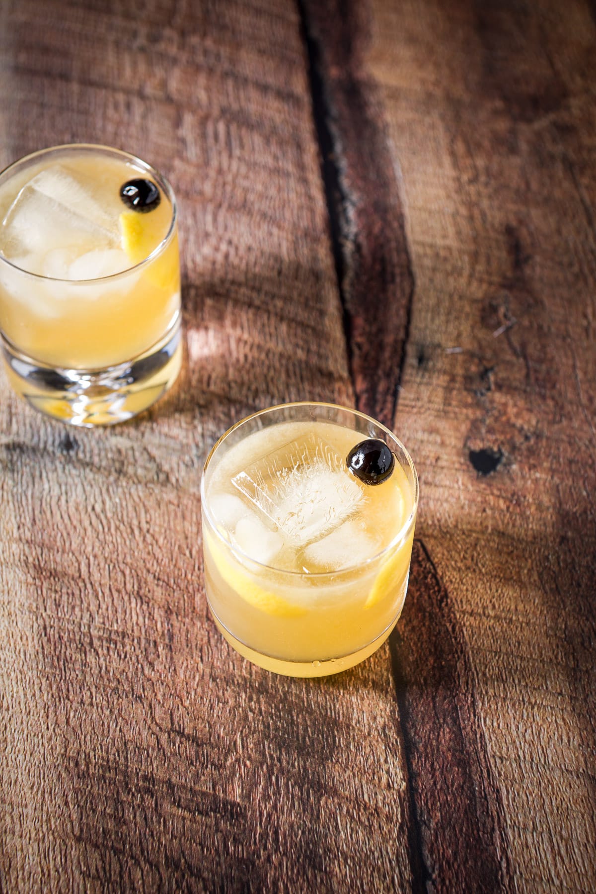 Higher view of the two cocktail glasses with the drink in it with lemon twists and cherries