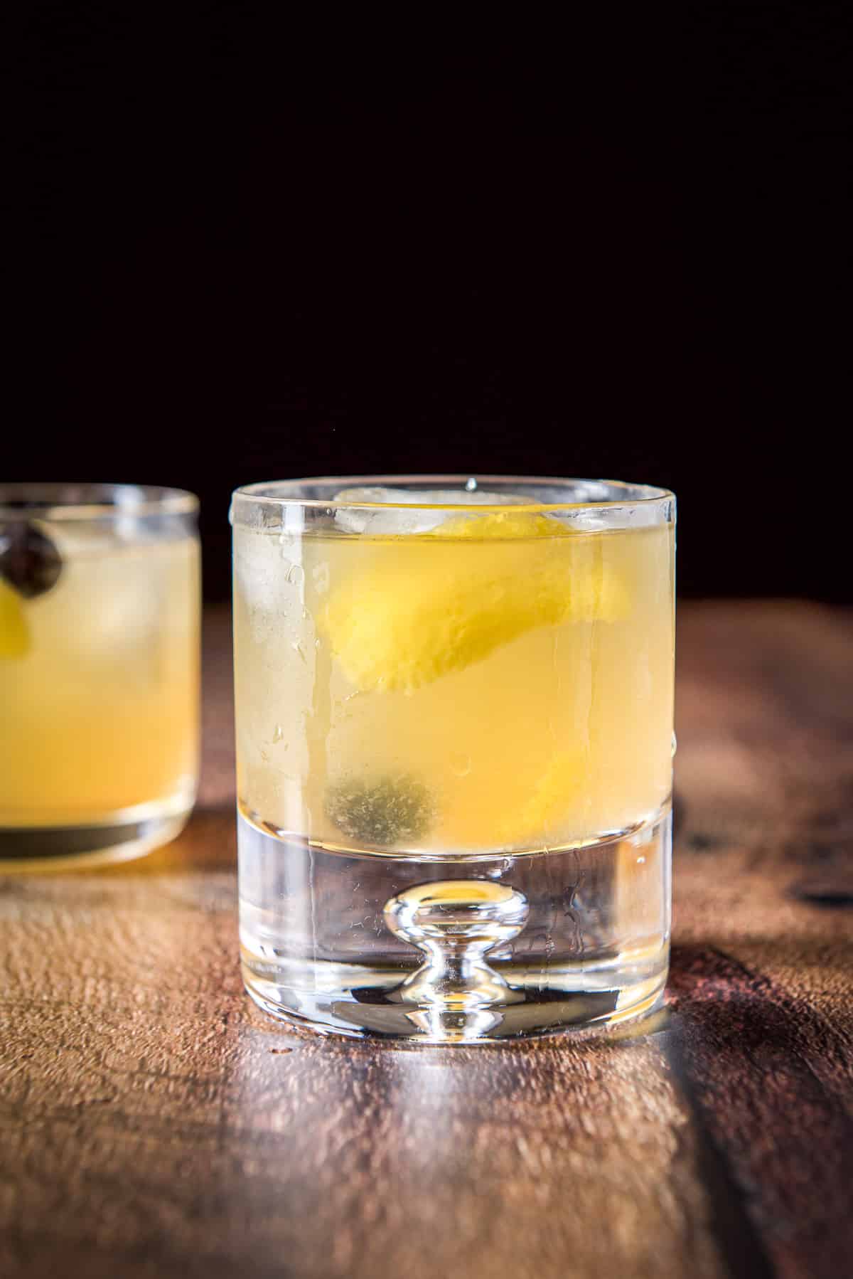 Vertical view of the bubble glass with the cocktail, lemon twists and cherries
