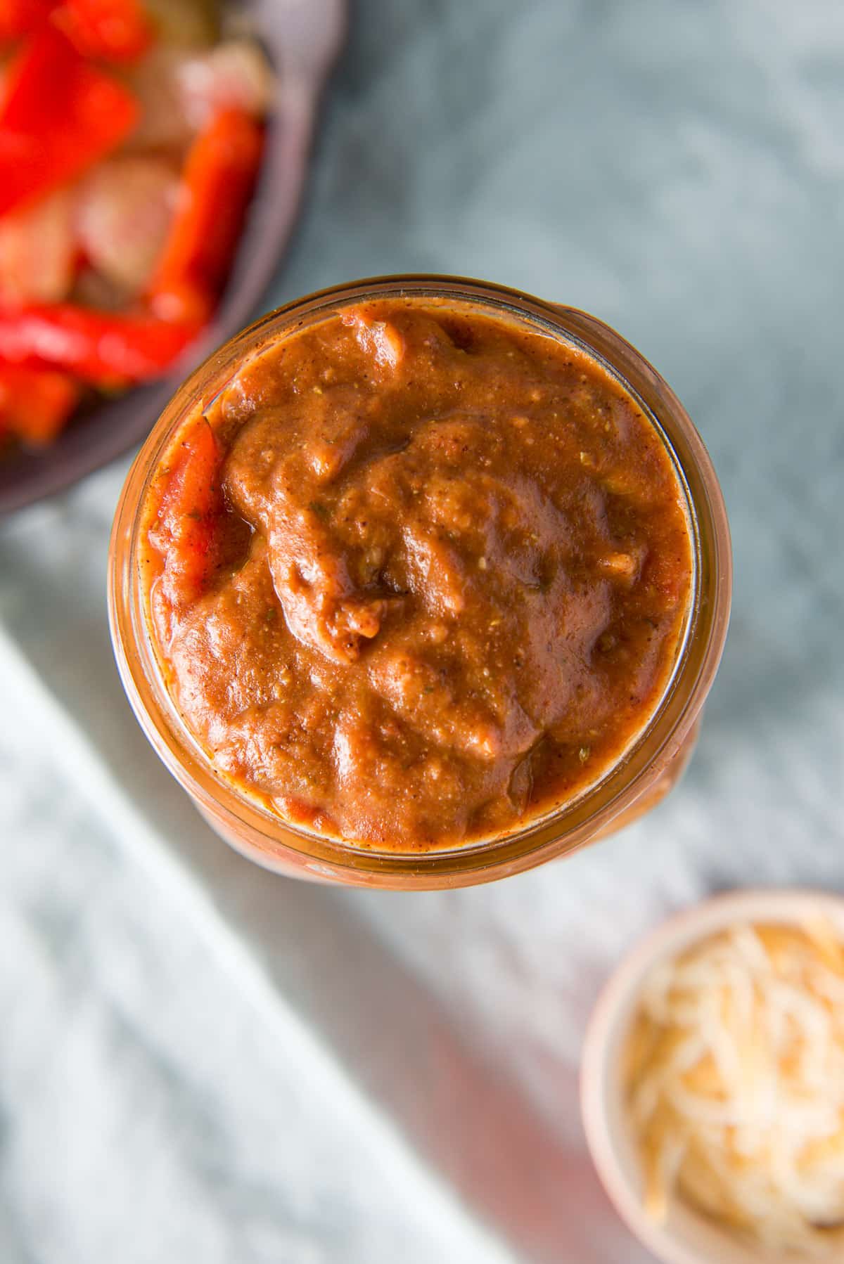 Overhead view of a jar of sauce, cheese and vegetables in a pan