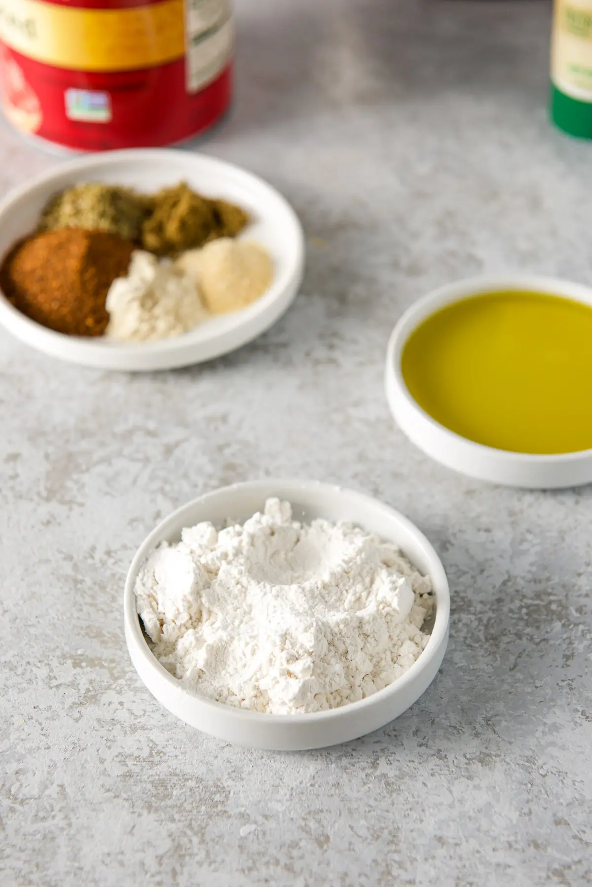 Flour, olive oil, spices and herbs in small white plates