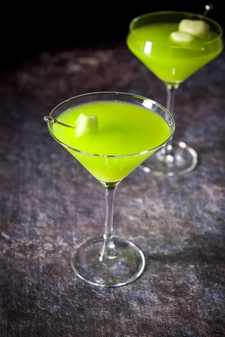 Classic glass in front of the fancy glass filled with the melon drink with the melon as garnish