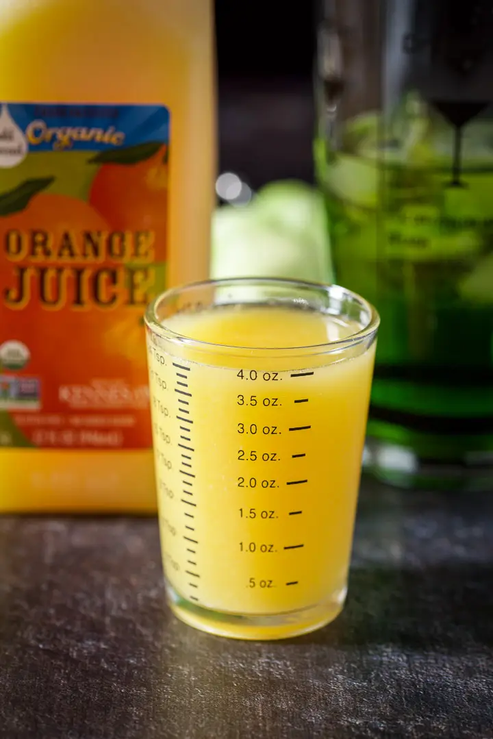 Orange juice measured out with the carton and shaker in the background
