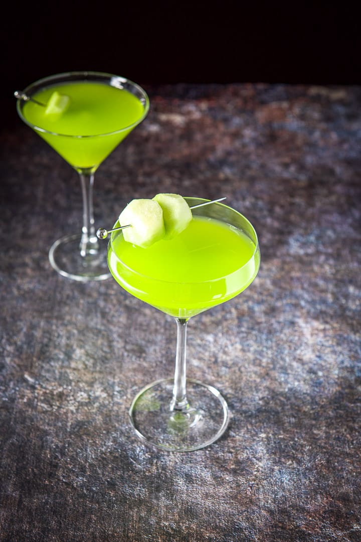 The curved glass in front of the classic glass filled with the green cocktail