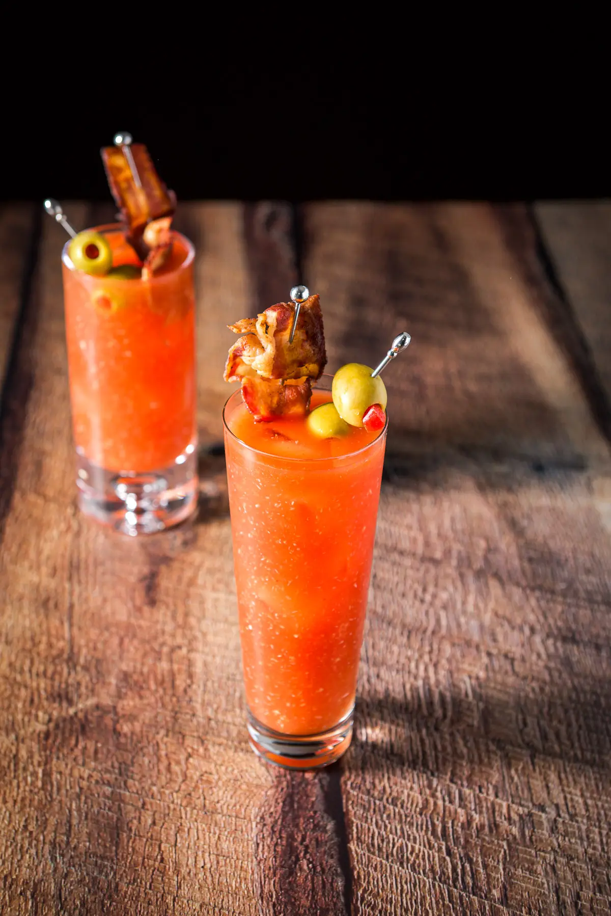 Two tall glasses with the bloody mary in them with garnish on picks