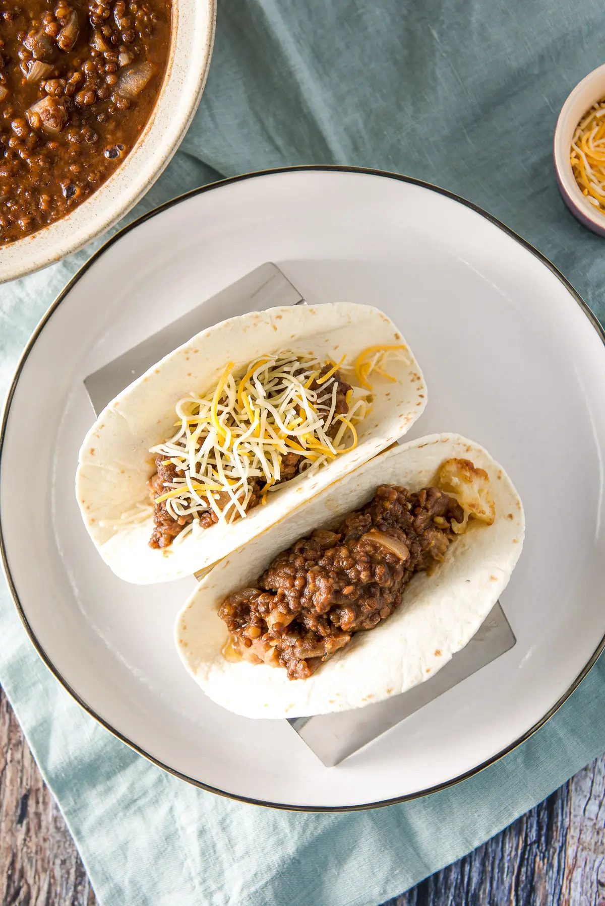 Overhead view of a plate with two tacos on it with lentils off the the side